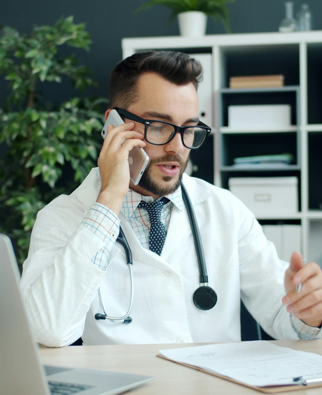 A doctor at their clinic desk, phone in hand between patients
